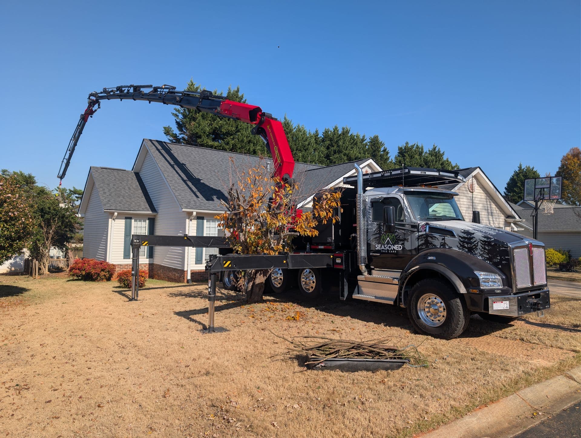 Palfinger crane lifting a large hardwood section out of a tight Greenville backyard