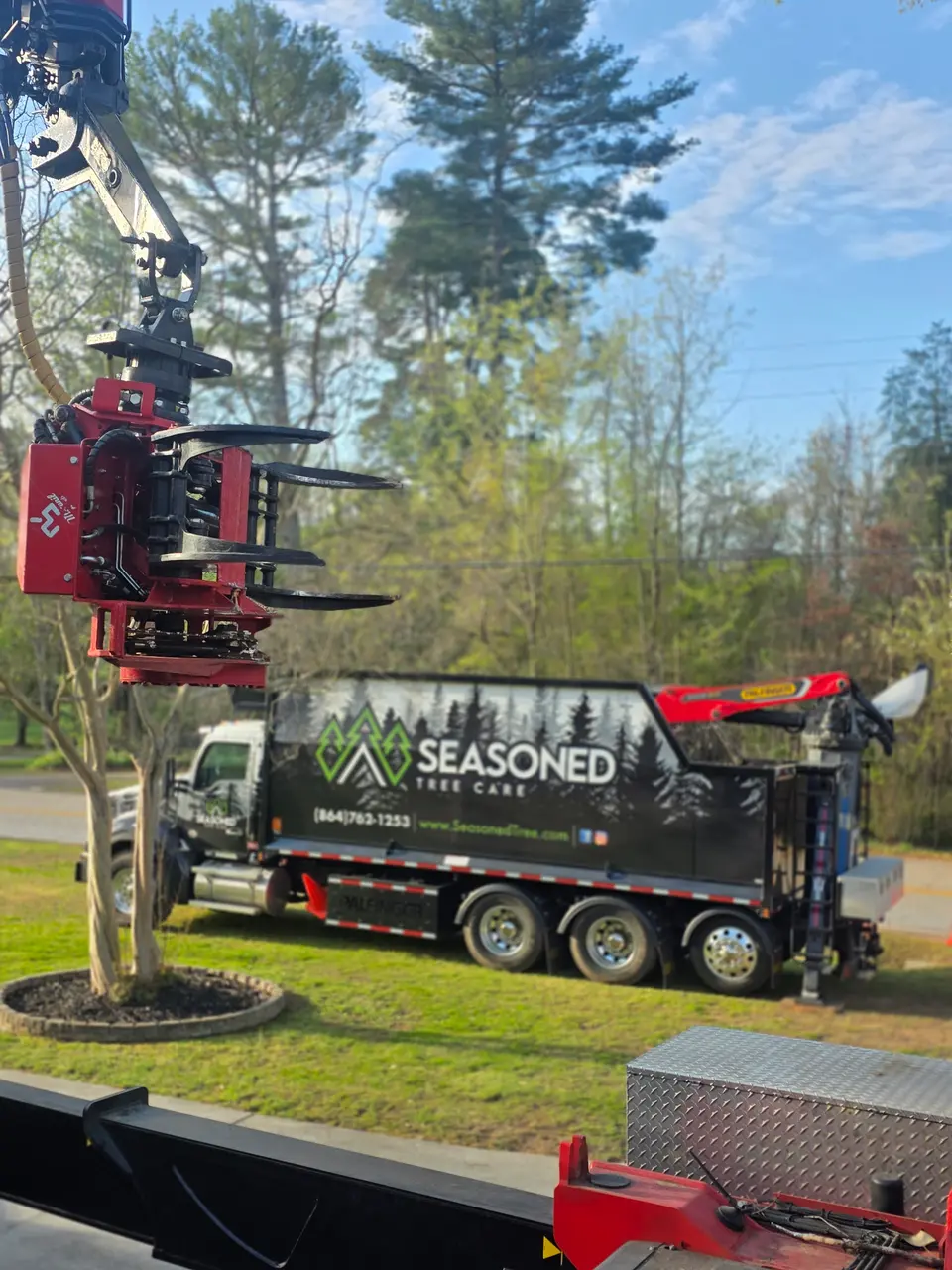 Our grapple saw head and a Seasoned Tree Care dump truck set up on a Greenville-area job.